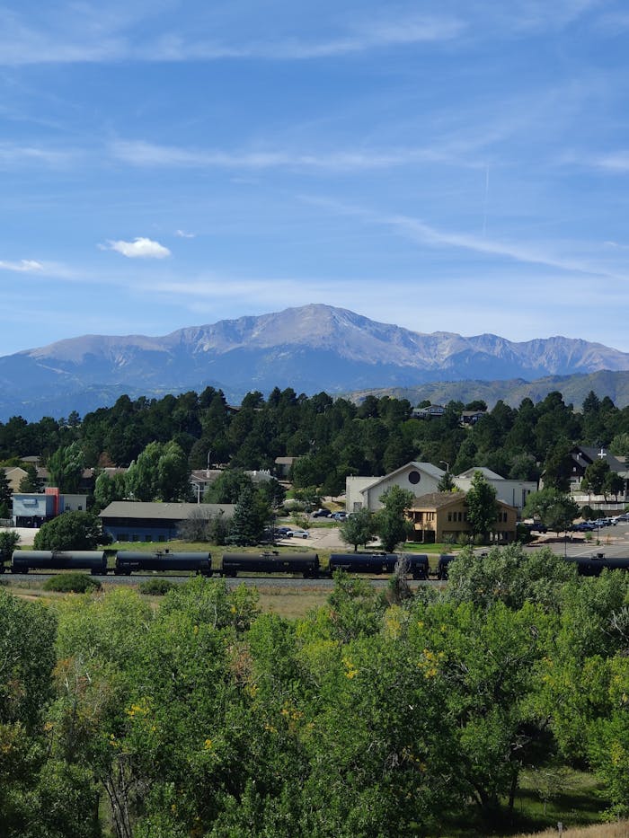 Beautiful view of Pikes Peak behind a town with lush greenery and clear blue skies.